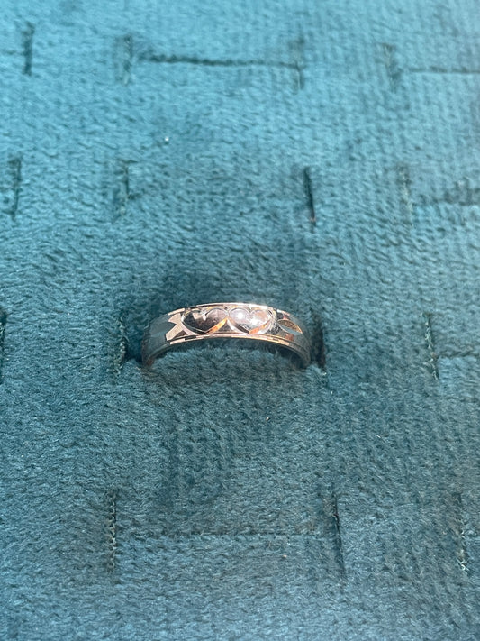 Silver ring with intricate design on a textured blue fabric background