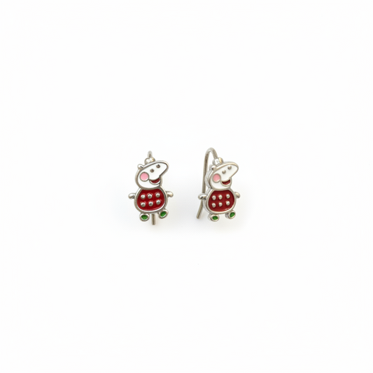 Two small turtle-shaped earrings on a person's finger against a red fabric background