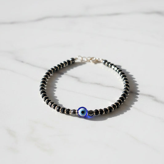 Beaded bracelet with a blue eye charm on a pink surface