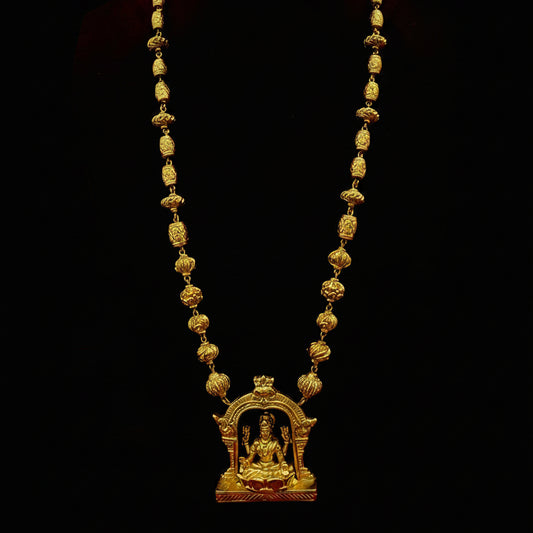Gold necklace with a decorative pendant on a red fabric background