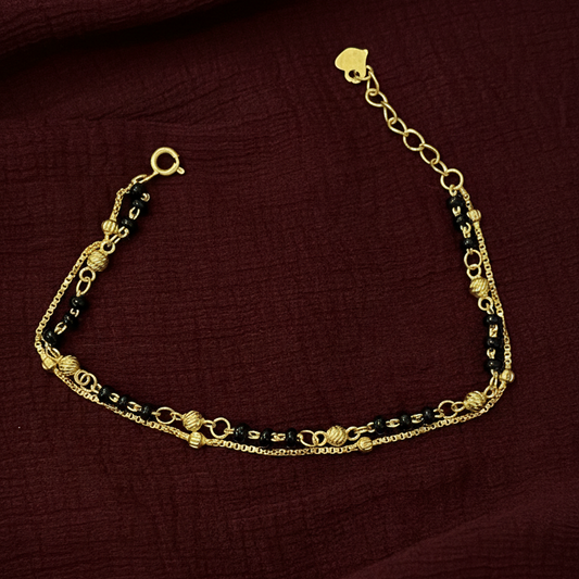 Gold bracelet with black beads on a red fabric background