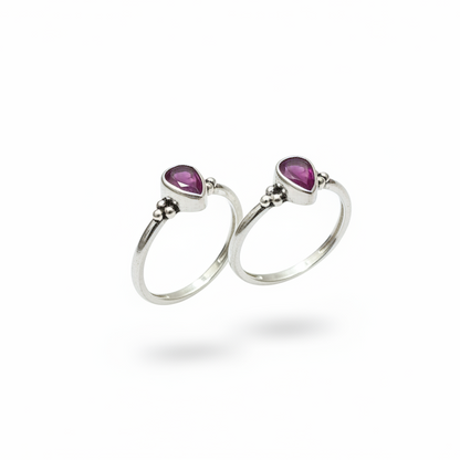 Two silver rings with purple gemstones on a white background