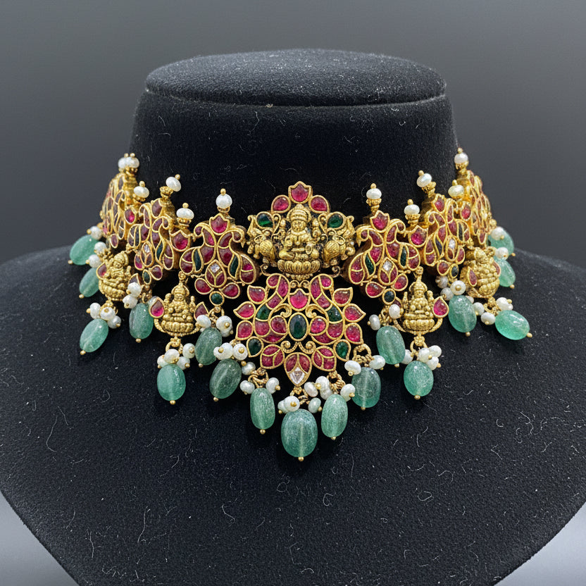 Ornate gold and gemstone jewelry piece on a pink velvet cushion