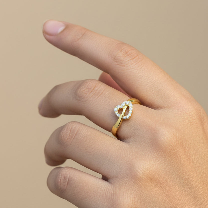 Gold ring with heart design on a finger against a red fabric background