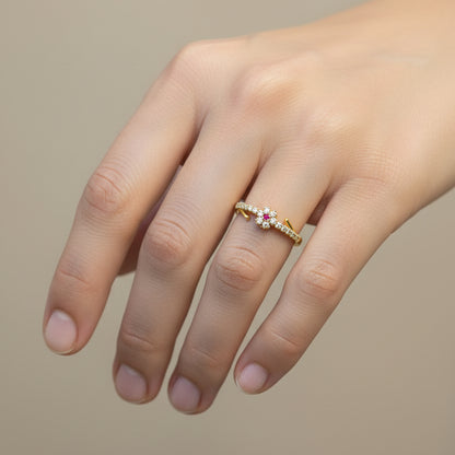 Gold ring with gemstones on a finger against a red fabric background
