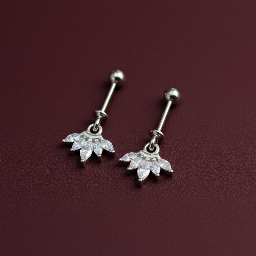 Pair of silver belly button rings with floral designs on a maroon background