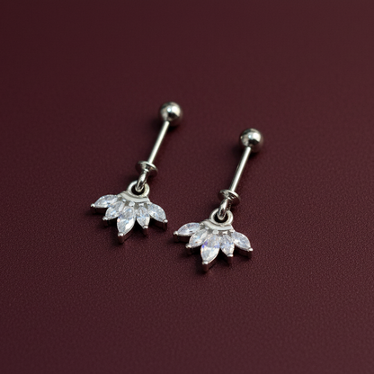 Pair of silver belly button rings with floral designs on a maroon background