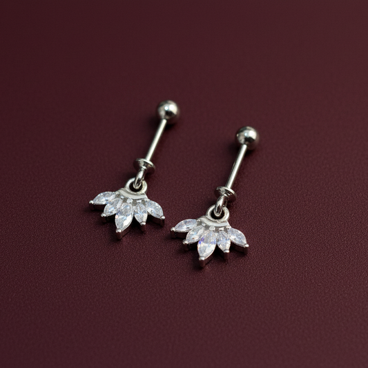 Pair of silver belly button rings with floral designs on a maroon background