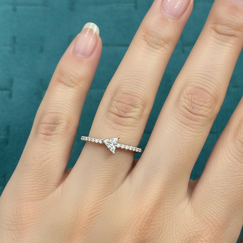 Hand wearing a diamond ring on a teal background