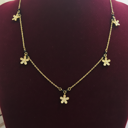 Gold necklace with floral pendants on a red cushion