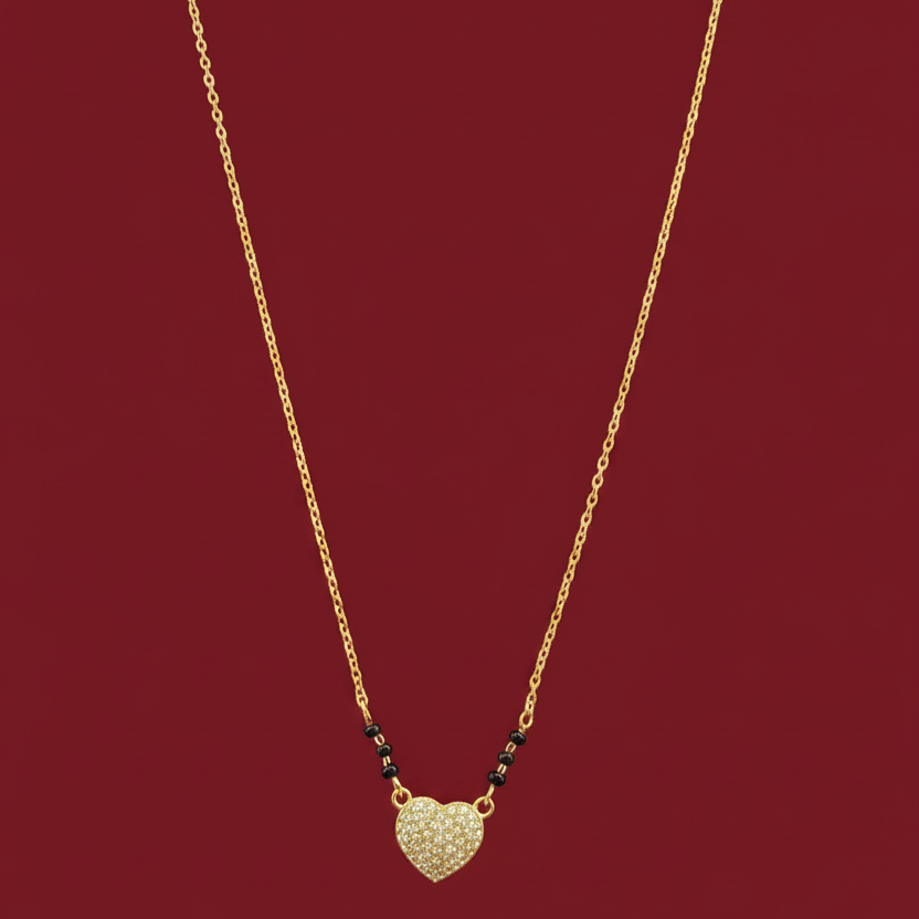 Gold necklace with a heart-shaped pendant on a red velvet surface