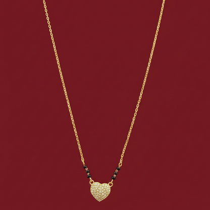 Gold necklace with a heart-shaped pendant on a red velvet surface