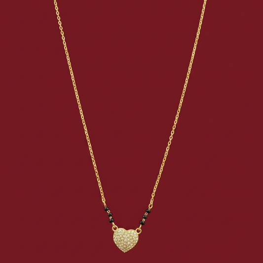 Gold necklace with a heart-shaped pendant on a red velvet surface