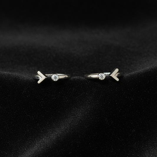 Two silver rings with arrow designs on a pink fabric background.
