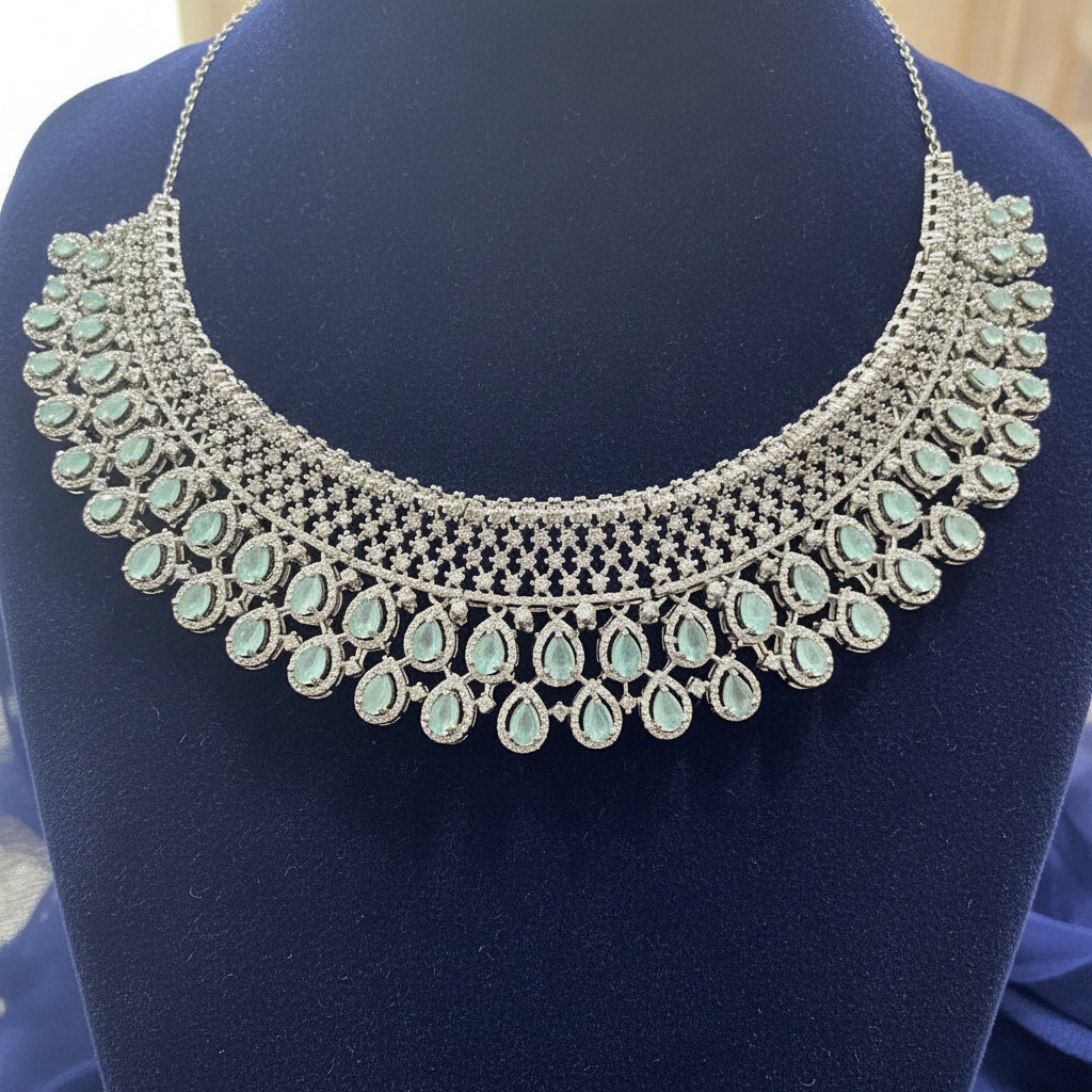 Silver necklace with green gemstones on a red velvet cushion