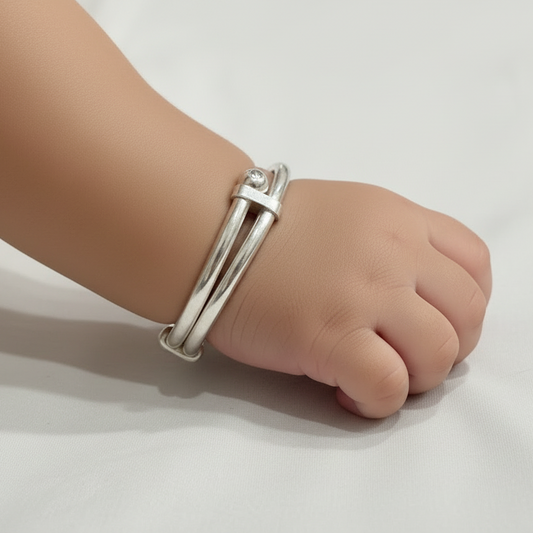 Child's foot wearing a silver anklet on a white background