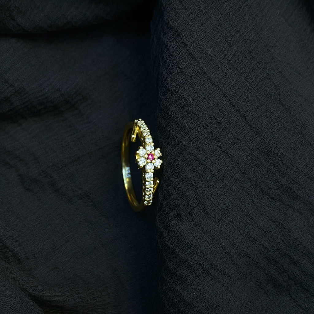 Gold ring with a red gemstone on a pink fabric background
