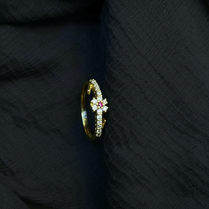 Gold ring with a red gemstone on a pink fabric background