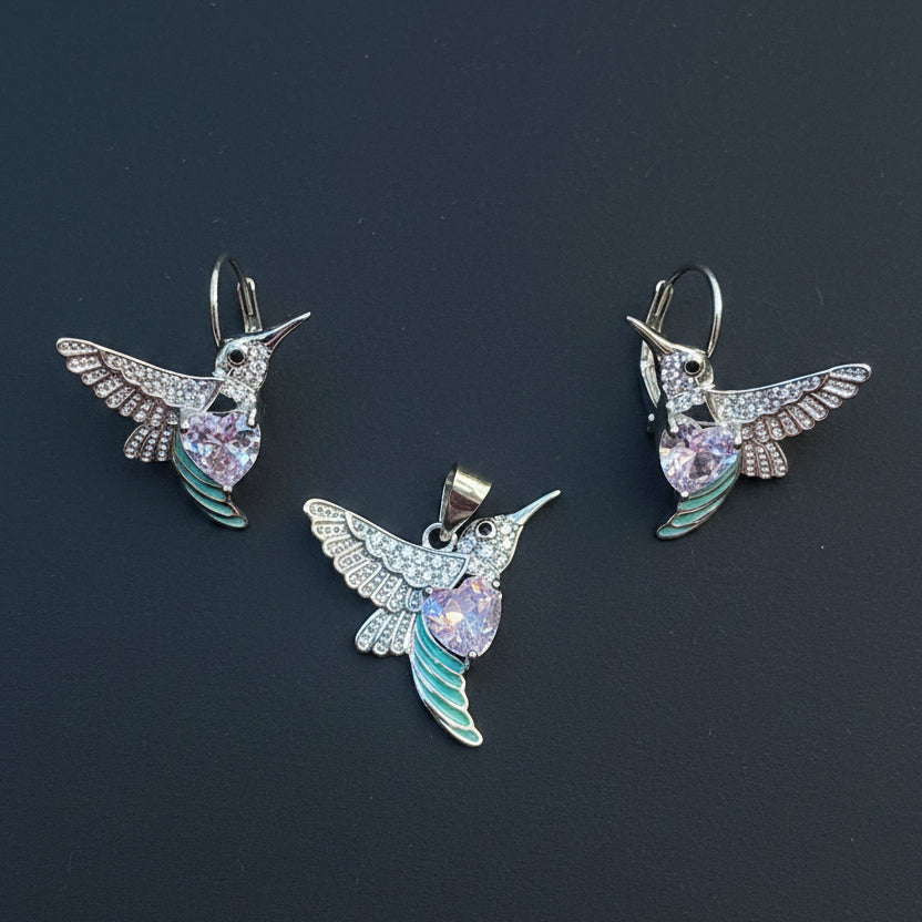 Three hummingbird-shaped earrings on a red fabric background