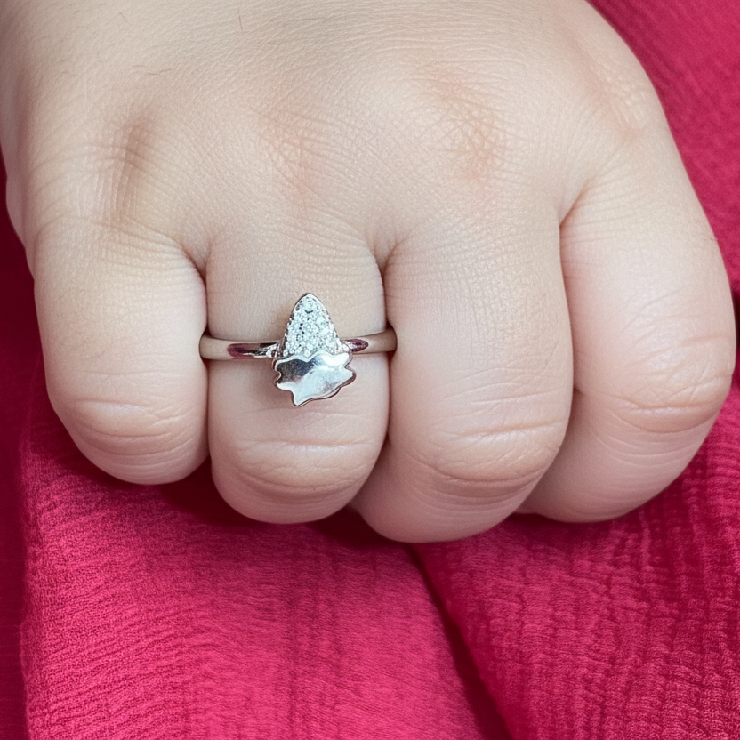 Hand wearing a silver ring with a unique design on a red fabric background
