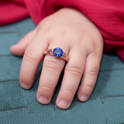 Hand wearing a ring with a blue gemstone on a textured surface