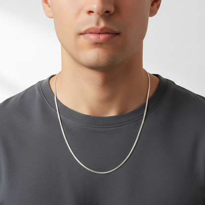 Man wearing a silver chain necklace against a plain background