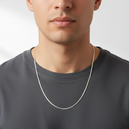Man wearing a silver chain necklace against a plain background