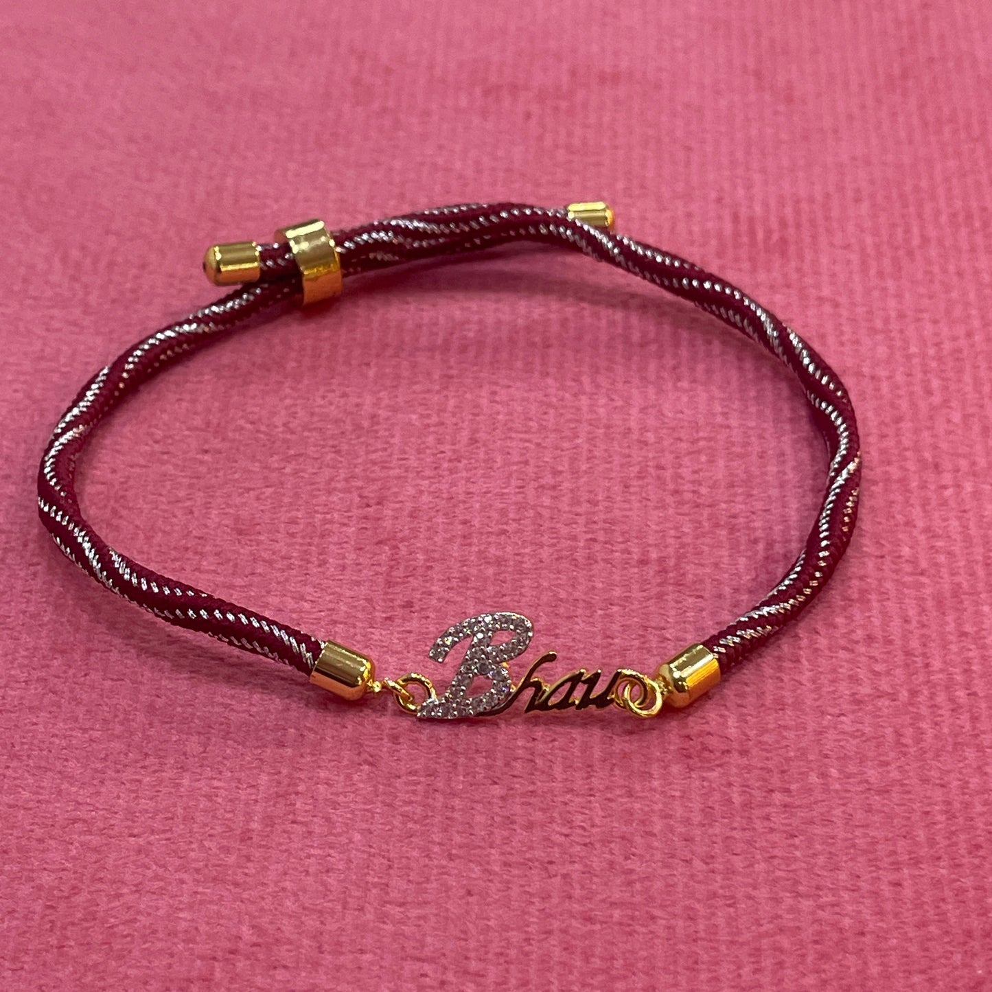 Gold-Plated Bhaiya Name Rakhi for Brother | CZ Script Charm on Maroon & Gold Twisted Thread