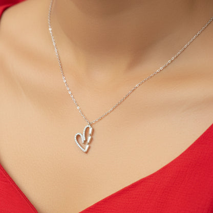 Silver necklace with a heart and arrow pendant on a red fabric background