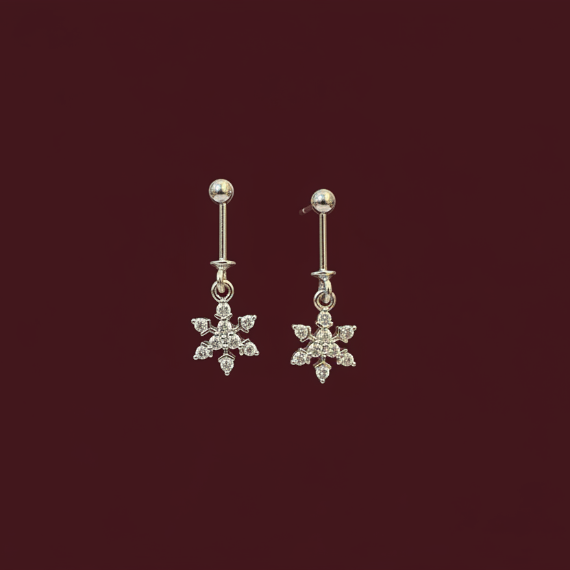 Pair of silver snowflake earrings on a dark red background
