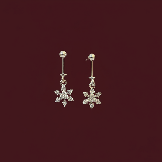 Pair of silver snowflake earrings on a dark red background