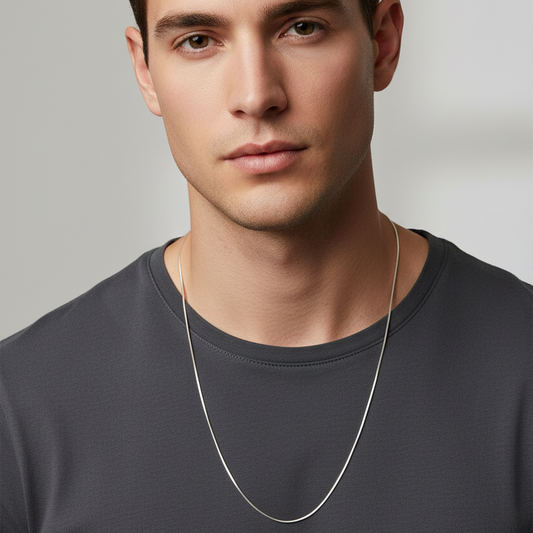 Man wearing a dark gray shirt and a silver necklace against a neutral background