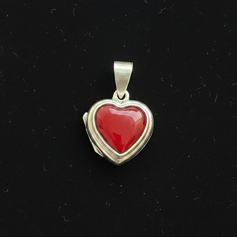 Heart-shaped pendant with red stone on a red fabric background