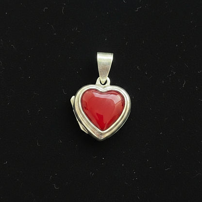 Heart-shaped pendant with red stone on a red fabric background