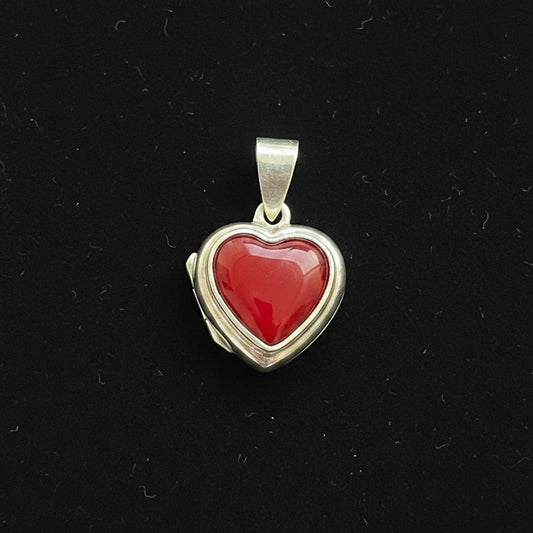 Heart-shaped pendant with red stone on a red fabric background