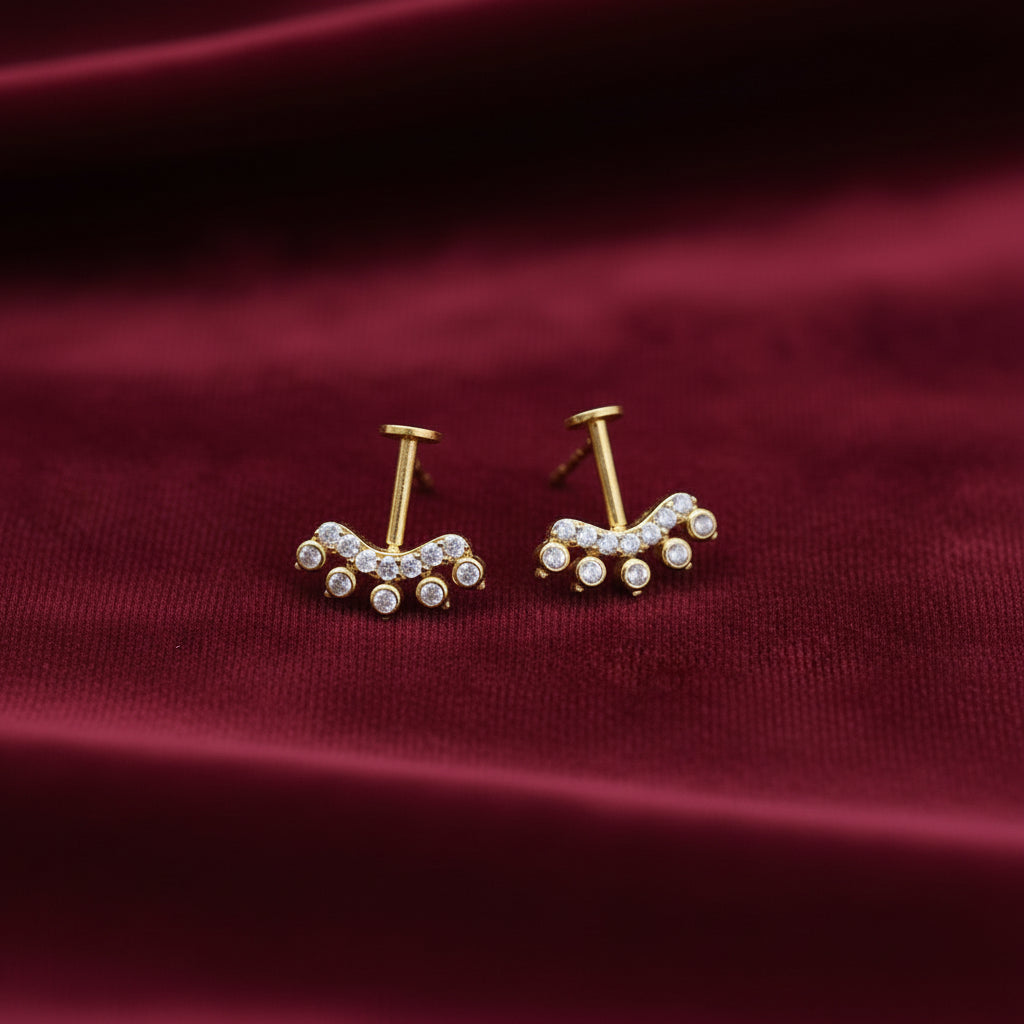 Pair of gold plated on silver bugadi earrings with gemstones on a maroon background