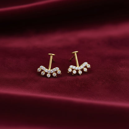 Pair of gold plated on silver bugadi earrings with gemstones on a maroon background