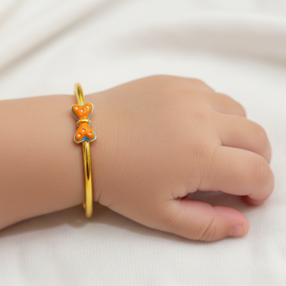Gold bracelet with orange accents on a child's wrist against a white background