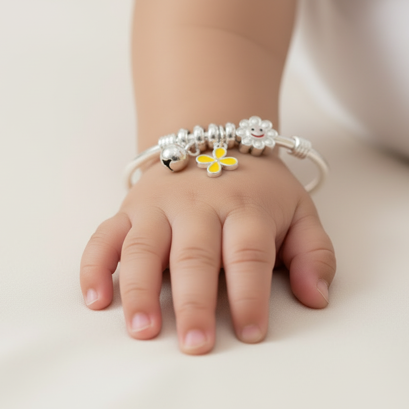 Child's hand wearing a bracelet with a yellow flower charm on a light background