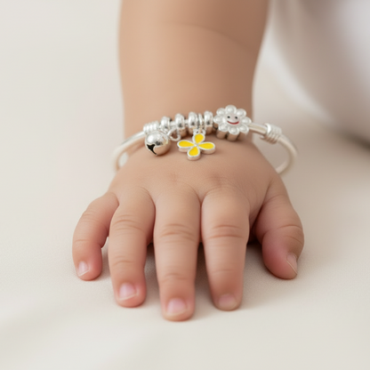 Child's hand wearing a bracelet with a yellow flower charm on a light background