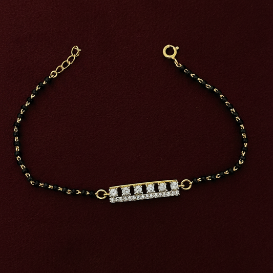 Gold and black beaded bracelet with a diamond clasp on a red background