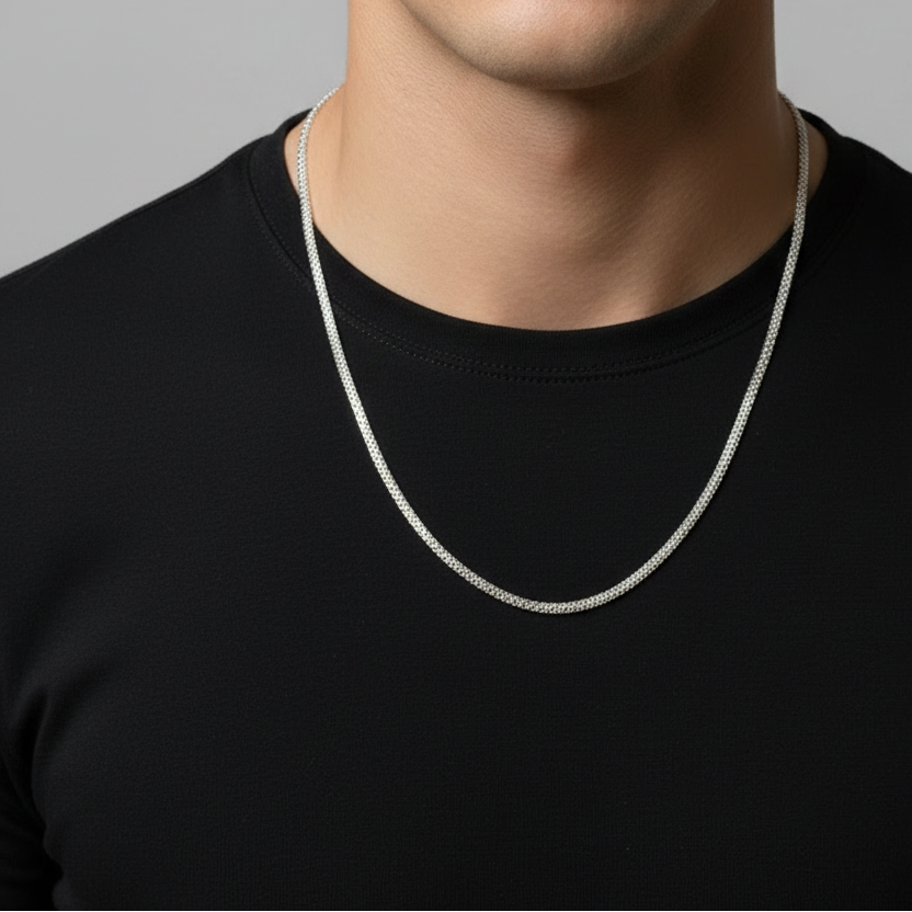 Man wearing a silver necklace against a gray background