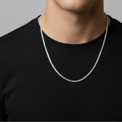 Man wearing a silver necklace against a gray background