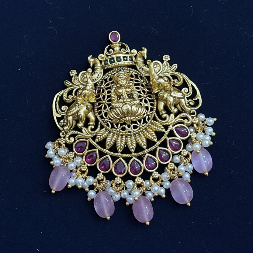 Decorative brooch with gold, purple, and pearl details on a pink fabric background