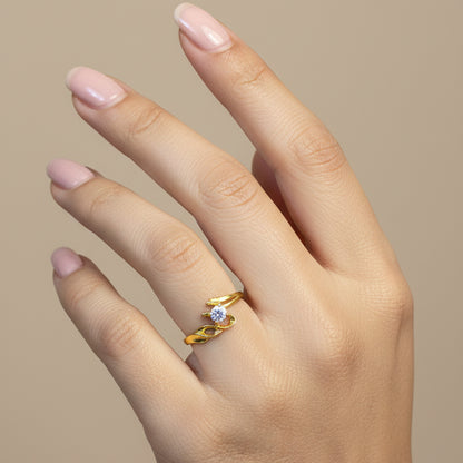 Gold ring with a diamond on a finger against a red fabric background