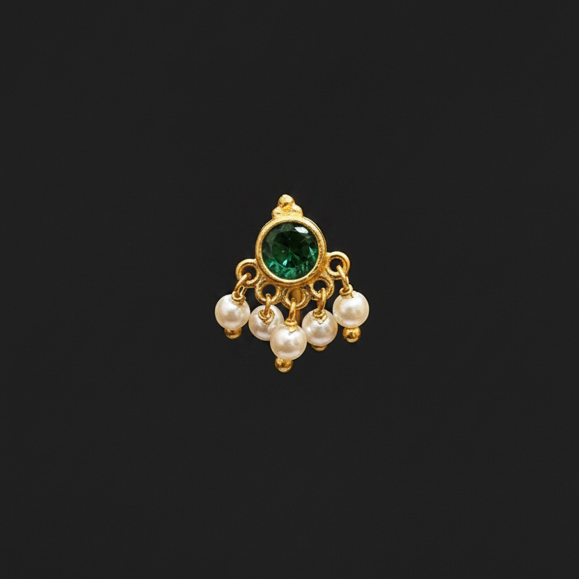 Gold ring with green gemstone and pearls on a finger against a red fabric background