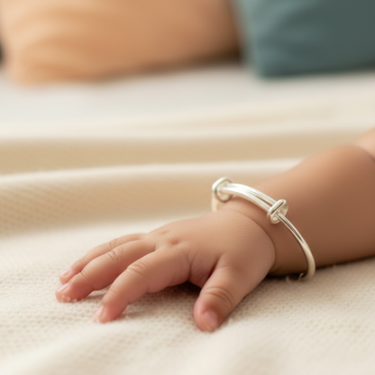Baby's hand wearing a silver bracelet on a soft surface