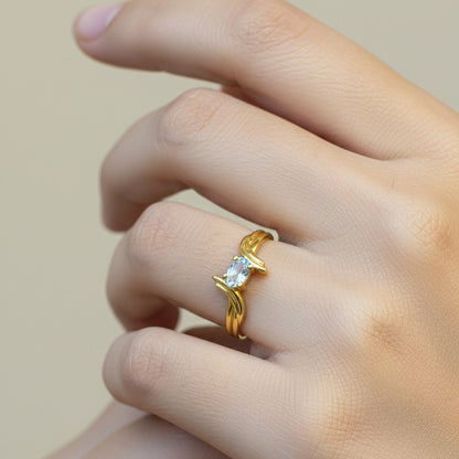 Gold ring with a diamond on a person's finger against a red fabric background