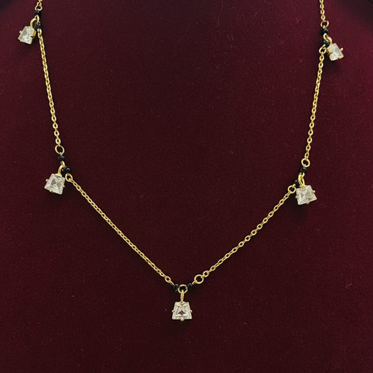 Gold necklace with diamond-like pendants on a red background