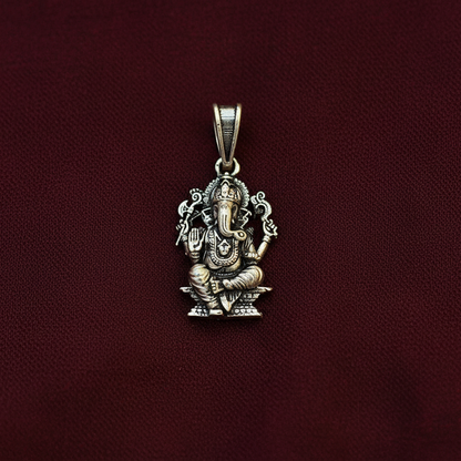Silver pendant with intricate design on a maroon background